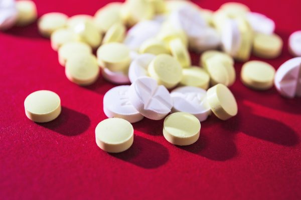 close-up-white-yellow-pills-red-background